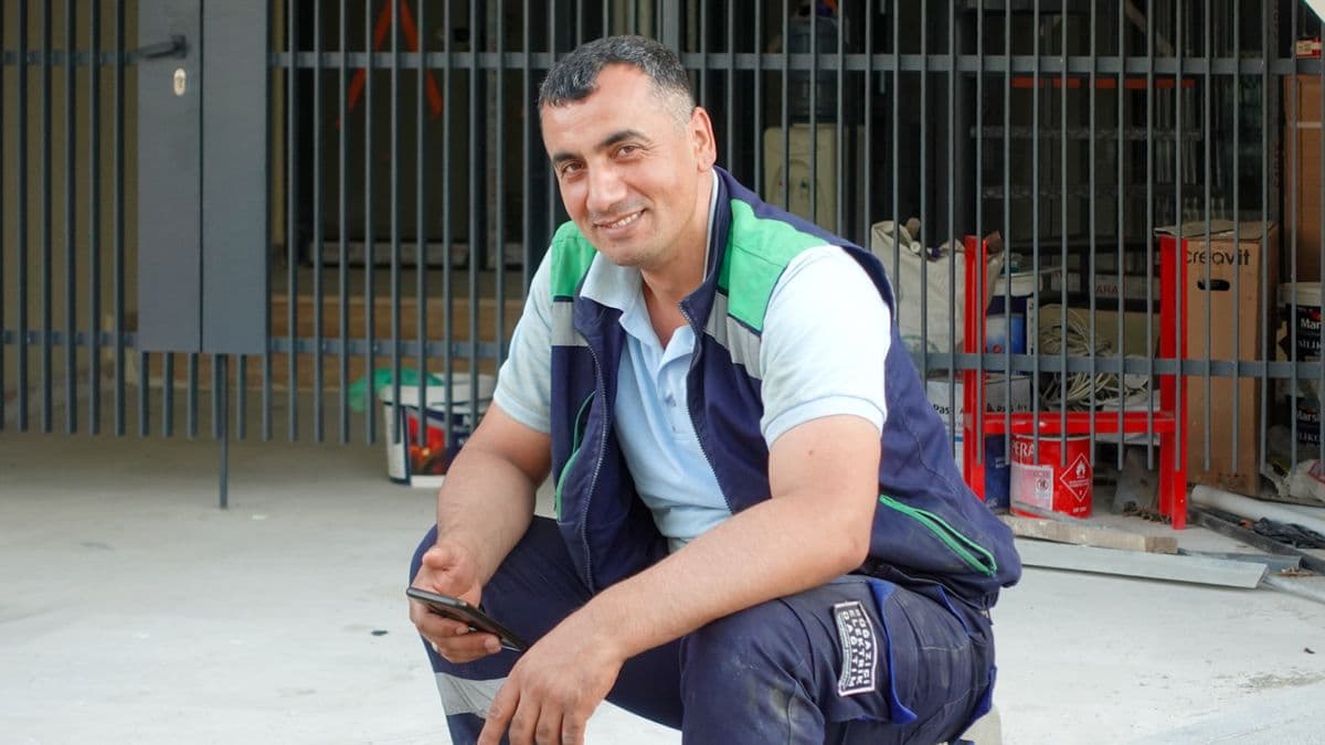 Profesional de reformas sonriendo con su móvil en obra